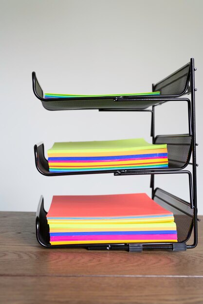 Stack of documents on brightly colored paper on stacked tray on office table