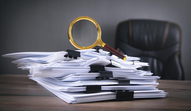 Stack of documents and magnifying glass on the table.