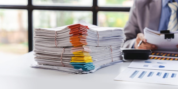 Stack of documents pile of papers on office desk employee's table closeup Asian people