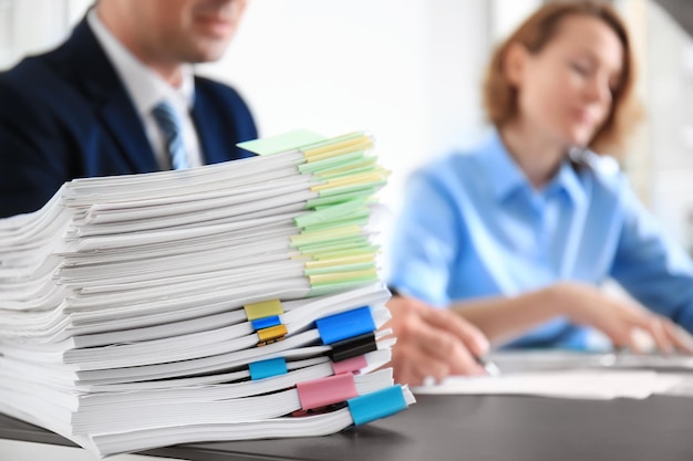 Photo stack of documents on table and blurred workers in office