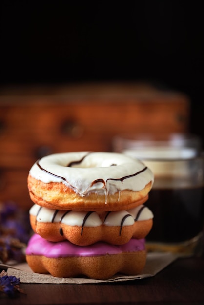 A stack of donuts with white frosting and a cup of coffee.