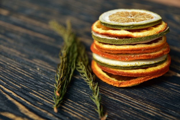 A stack of dried slices of orange and lime on a dark wooden 