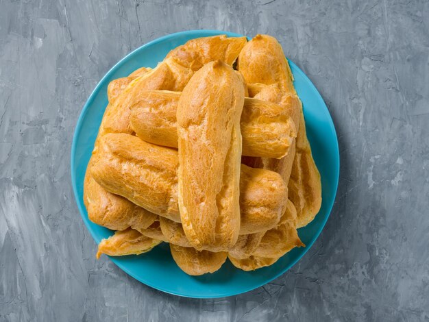 Stack of Eclairs on a blue plate on a gray background