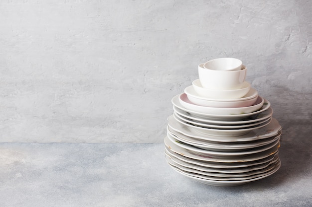 Stack of empty clean plates on a gray table with copy space.