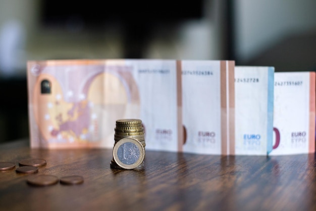 A stack of euro coins stands against the background of paper banknotes