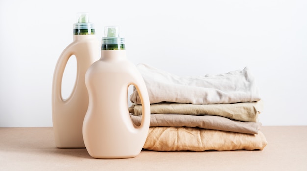 Stack of folded clean clothes things with Eco Design, blank bottles packaging of detergent for laundry