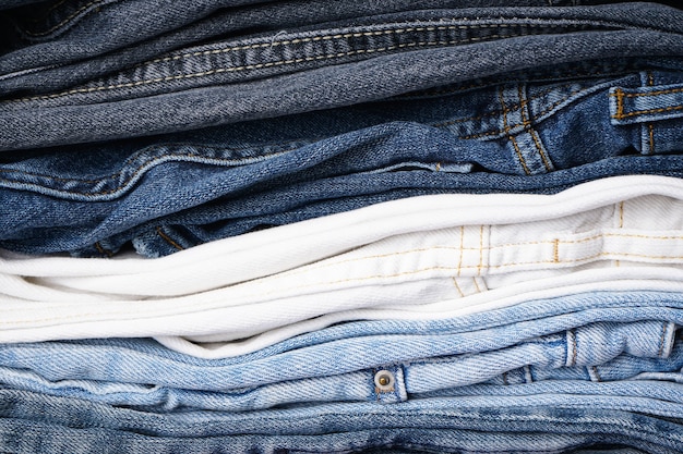 Stack of folded jeans, denim background.