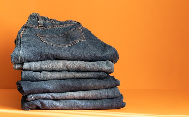 A stack of folded jeans on an orange background