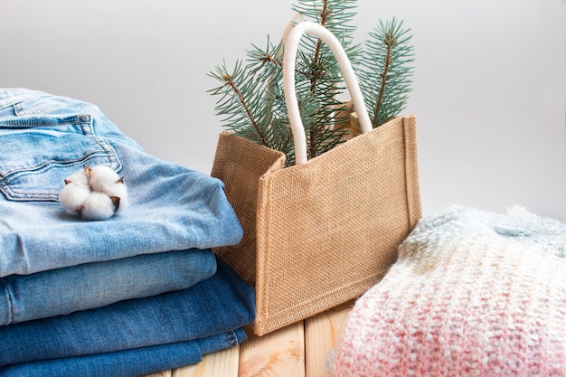 A stack of folded jeans in various shades of cotton with knitted hats and a sweater