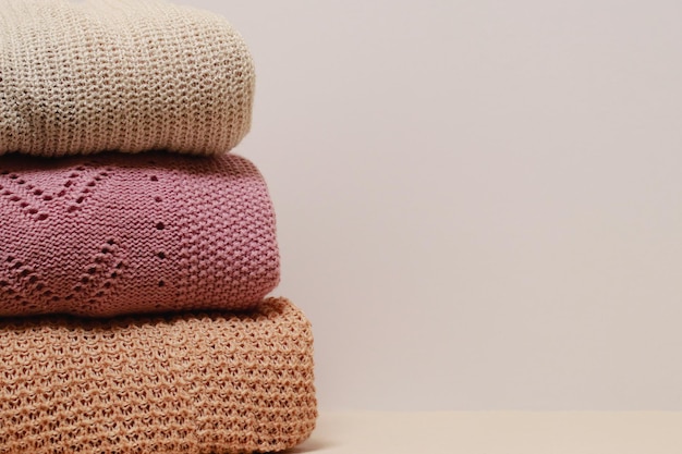 Stack of folded knitwear, minimal lifestyle, capsule wardrobe,\
copy space