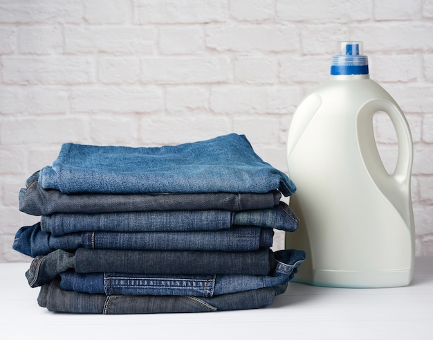 Stack of folded pairs of jeans and plastic detergent bottle