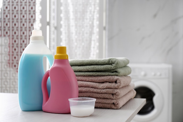 Stack of folded towels and detergents on white table in bathroom