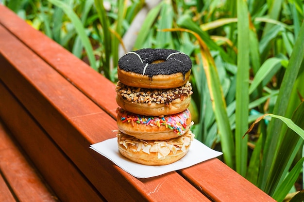 A stack of four donuts with different toppings on them.