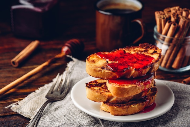 Pila di toast alla francese con sciroppo di frutti di bosco su piastra bianca