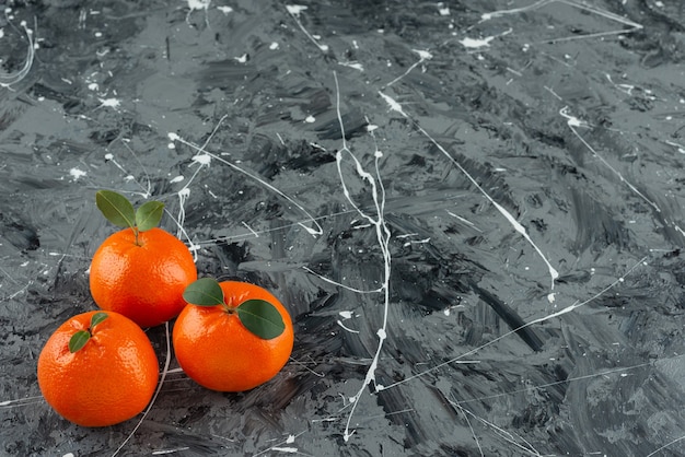 Stack of fresh tangerine fruits with leaves placed on a marble table .