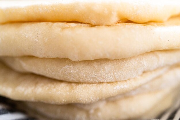 Stack of freshly baked flatbread wrapped in a kitchen towel.