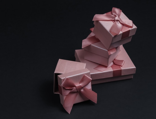 Stack of Gift boxes with bows on black studio background. Composition for christmas, birthday or wedding.