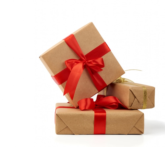 Stack of gifts wrapped in brown kraft paper and tied with silk ribbon