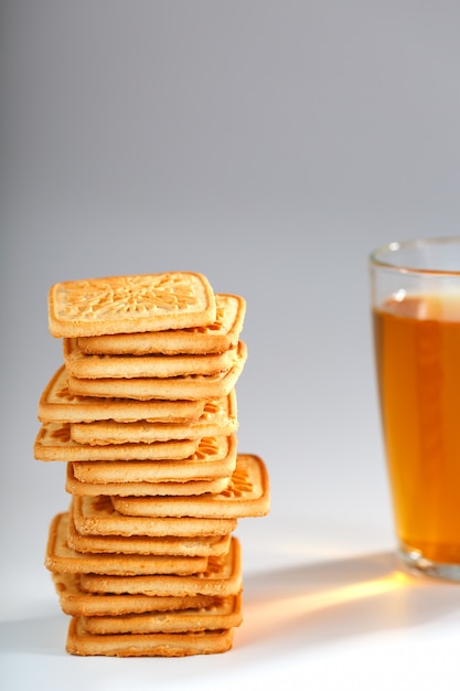 A stack of golden wheat cookies and a mug of fragrant green tea ion gray 