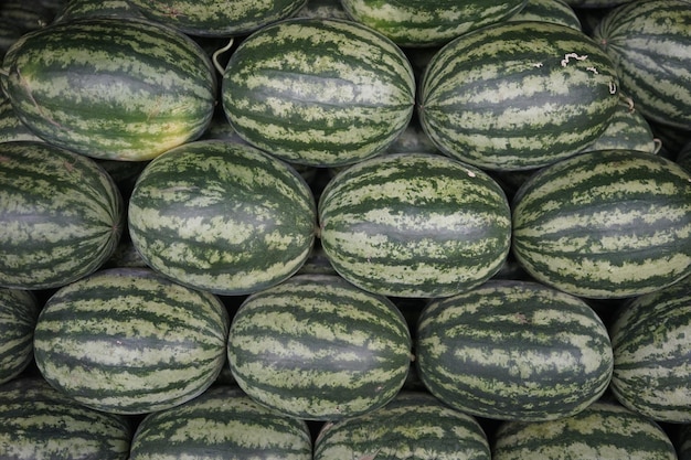 Photo a stack of green and white watermelons are stacked in rows.