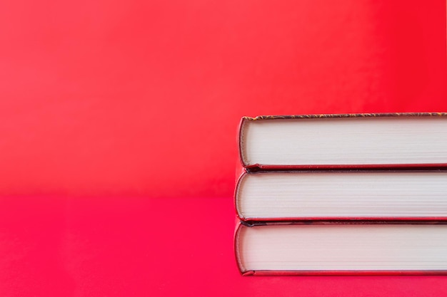 Stack of hardcover books on red background Copy space