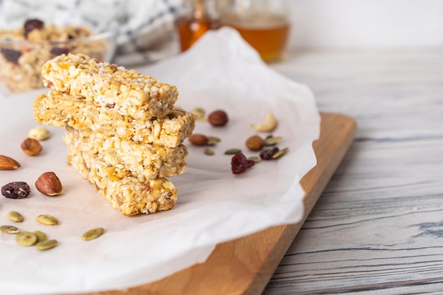Stack of healthy homemade granola bars with nuts, honey and dried fruit on wooden table