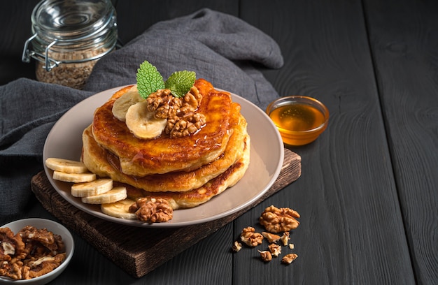 A stack of homemade pancakes on a black background. Side view, copy space.