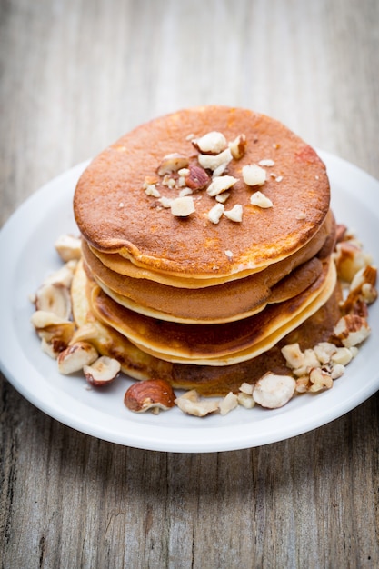 Stack of homemade pancakes with honey on wooden table.