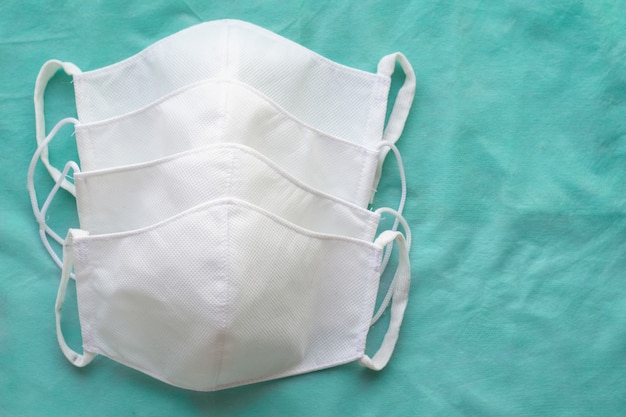 Stack of homemade protective reusable antiviral white masks on green cloth