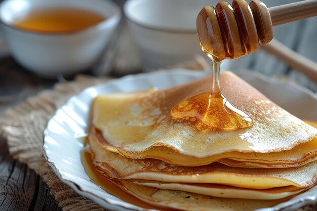 Stack of homemade thin pancakes on white plate honey pouring from above sweet treat Shrovetide week