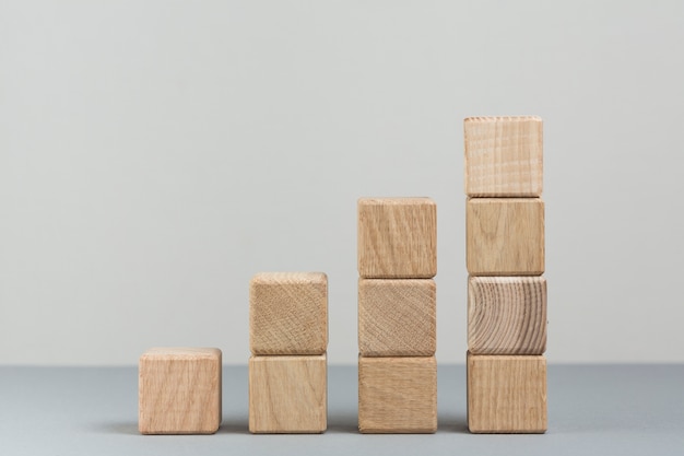 Stack of increasing wooden block on grey background