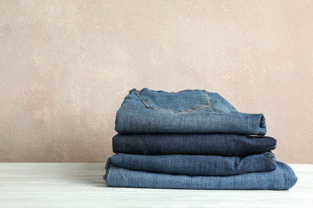 Stack of jeans pants on white table