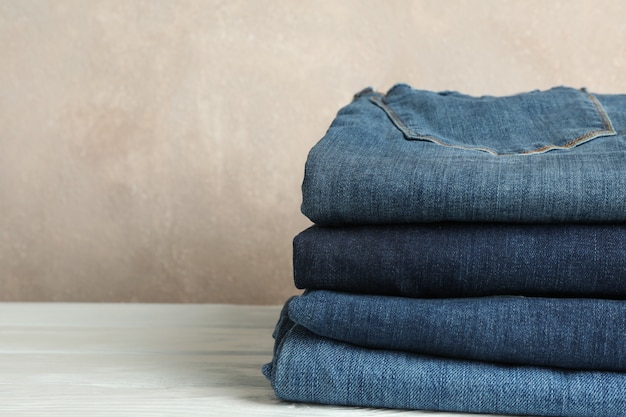 Stack of jeans pants on white table