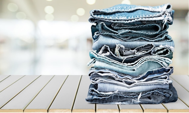 Stack of jeans on wooden table, close-up view