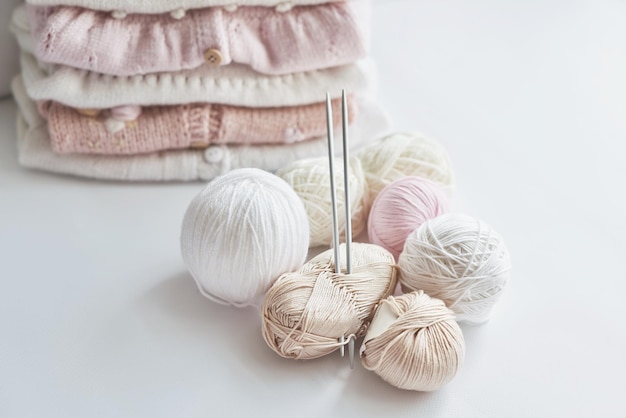 Stack of knitted clothes and balls of yarn knitting needles accessories for knitting Baby clothes Needlework hobby knitting handwork