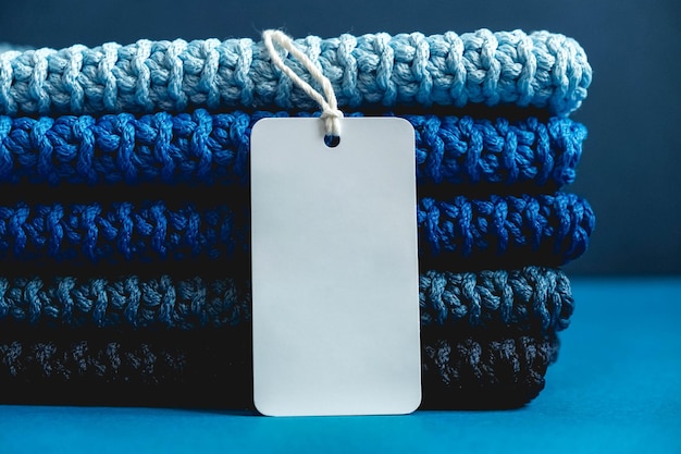 Foto pila di materiale lavorato a maglia da fili di colori grigio azzurro blu scuro con cartellino del prezzo in bianco