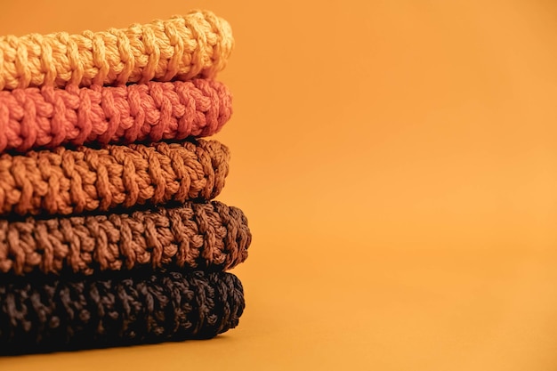 Stack of knitted material from threads of yellow orange brown colors on a orange background