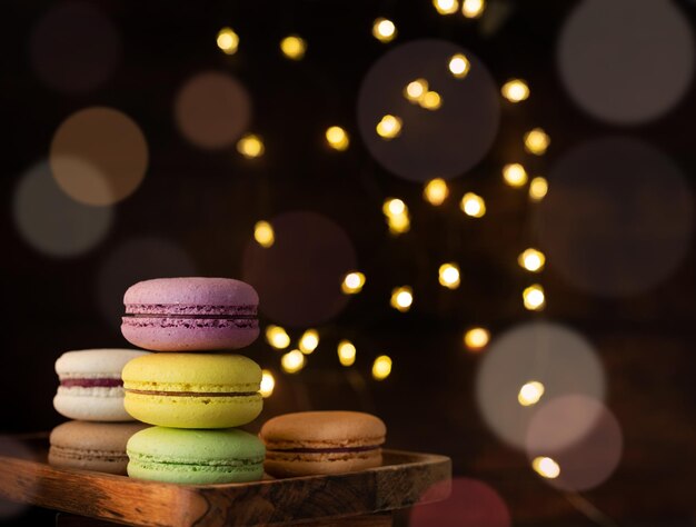 Photo stack of macaroons on the table fairy lights and bokeh background