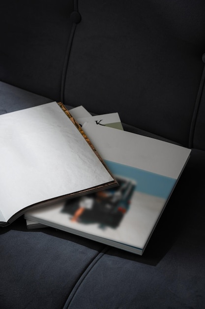 stack of magazines on a black leather couch in soft light