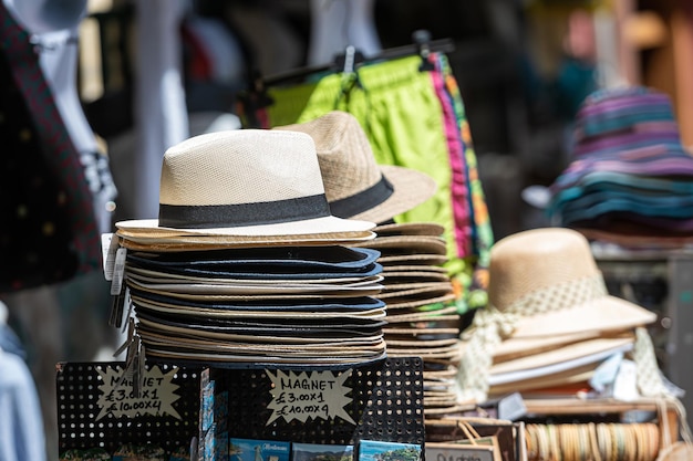 Pila di cappelli estivi per uomini e donne sul mercato di strada, messa a fuoco selettiva, sfondo sfocato