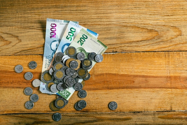 Stack of Mexican coins and bills on wooden table