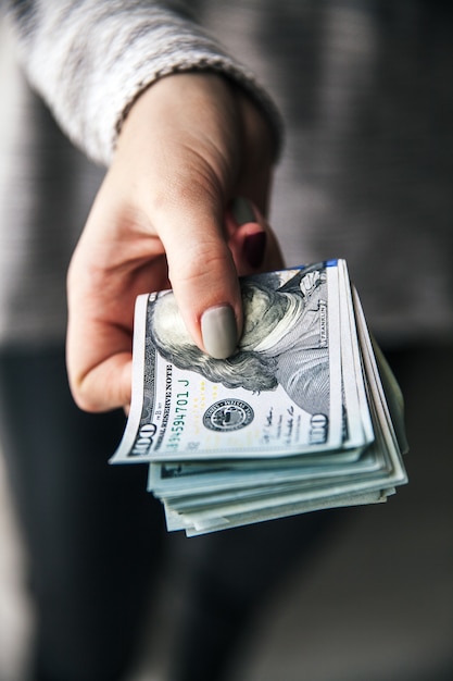 A stack of money, dollars in beautiful female hands. With a beautiful manicure. Business offer. Modern fashion.