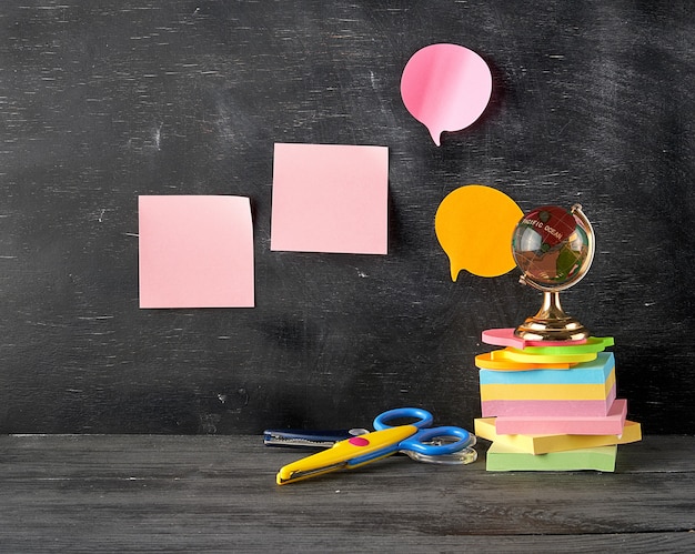 Stack of multi colored sticky stickers, glass globe, scissors