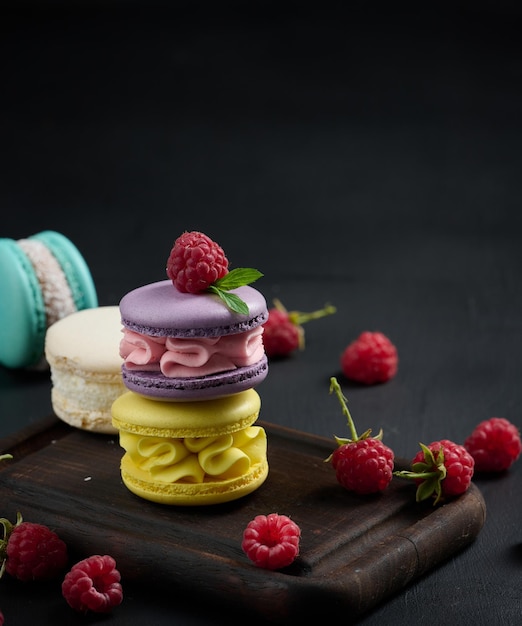 A stack of multicolored macaroons on a wooden board Delicious dessert