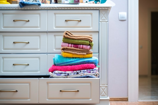 Стопка новых чистых полотенец свежего цвета на полке в прачечной