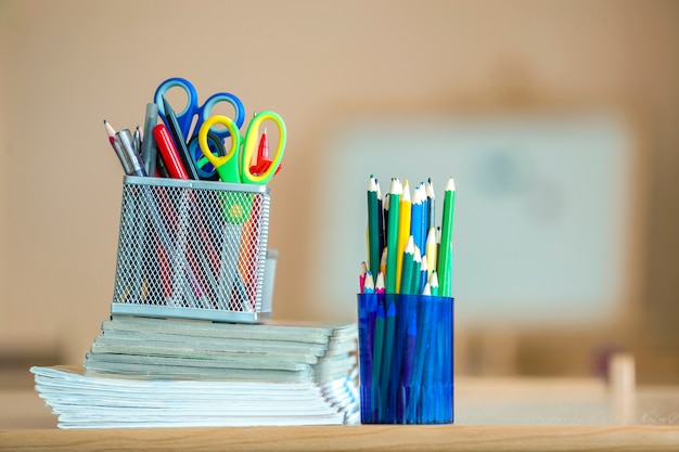 Stack of notebooks, colorful drawing pencils and stationery arrangement on copyspace .