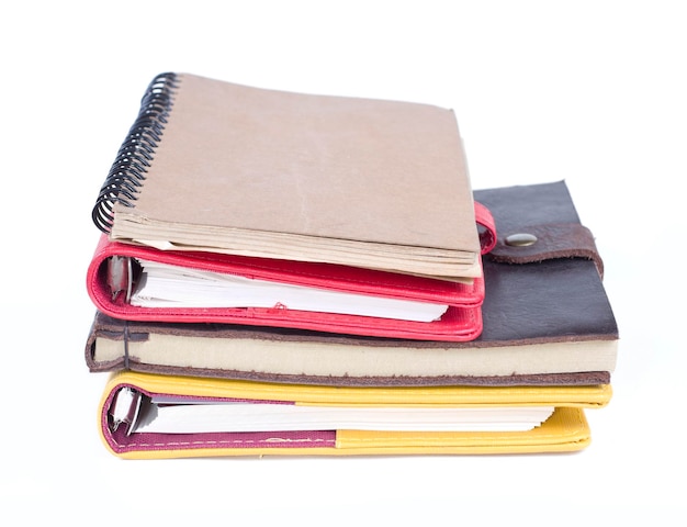 A stack of notebooks with a spiral bound notebook on top of them