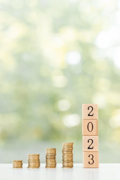 写真 新年のメッセージ2023ビジネスの成長新しい始まりと木製のテーブルの上のコインのスタック