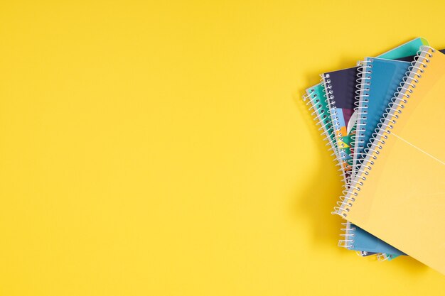 Фото Стек красочных ноутбуков на желтом фоне плоский вид сверху