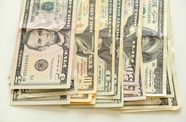 Фото Стек долларовых купюр на белом фоне. банкнота в сто, пятьдесят, двадцать, десять, пять долларов. закройте вверх высокого разрешения новой стодолларовой банкноты.
